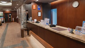 A hotel reception desk with a clock, informational signs, and a clear path for accessibility.