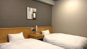 A hotel room with two beds, a nightstand, a lamp, and a wall-mounted mirror.