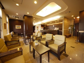 Um saguão de hotel com áreas de estar, uma mesa de recepção e um relógio na parede.