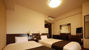 Habitación de hotel con dos camas, un escritorio, una silla, un espejo y un equipo de aire acondicionado.