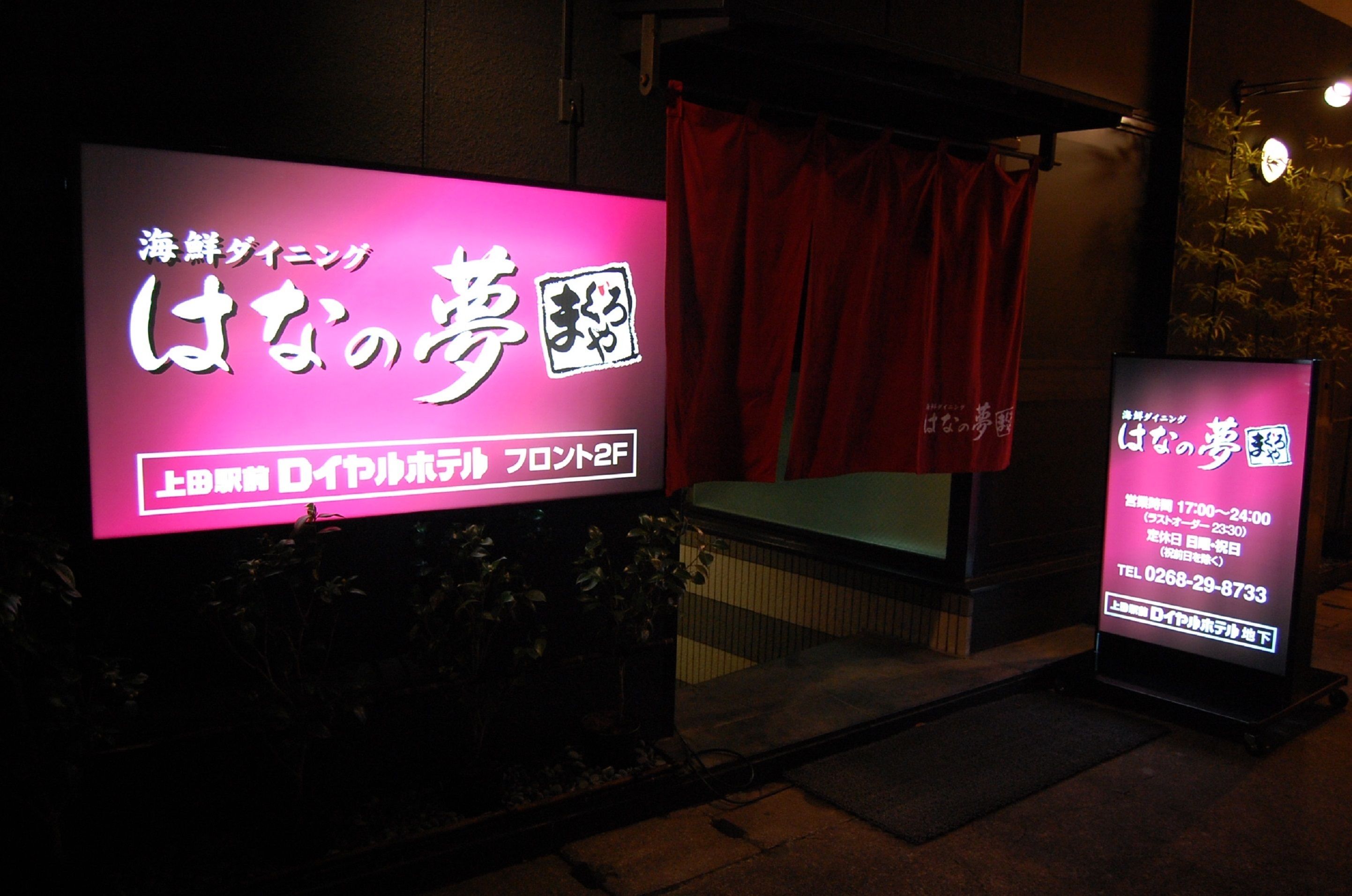 A brightly lit sign with Japanese characters, indicating a business or establishment.
