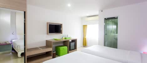 Habitación de hotel con dos camas, un escritorio con ordenador, televisor y ventana con cortinas.