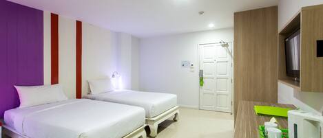 A hotel room with two beds, a wooden desk with a green tray, a white kettle, and a television on the wall.