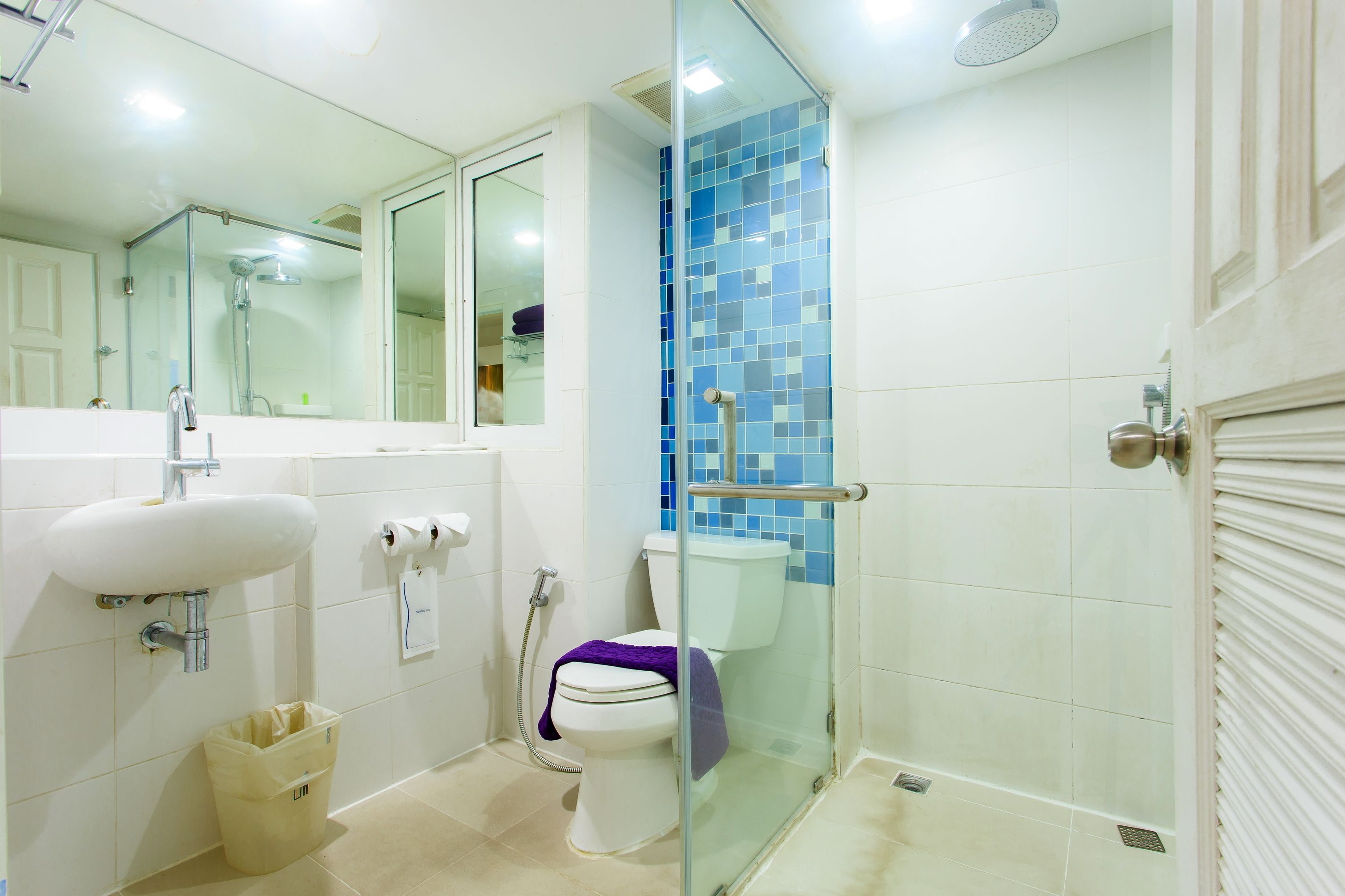 Ein Badezimmer mit einer Duschkabine, einem weißen Waschbecken und einer Toilette.