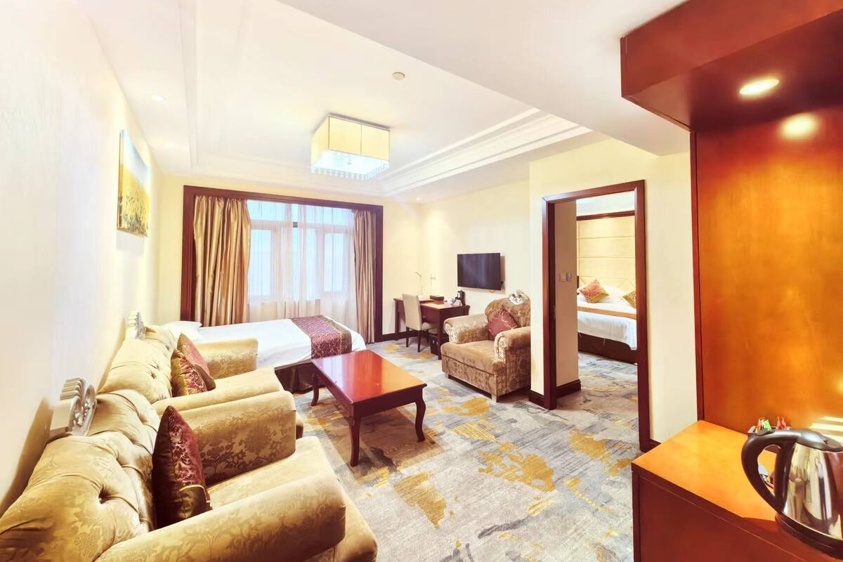 Een hotelkamer met een bed, een slaapbank, een salontafel, een televisie en een bureau.