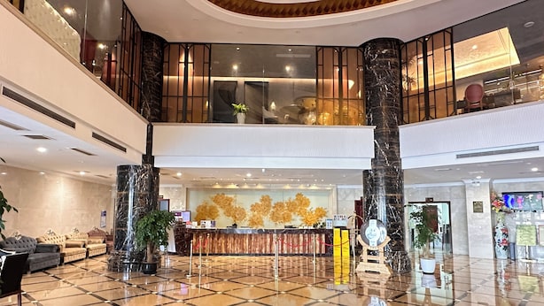 A spacious lobby with a checkered floor, a reception desk, and a staircase leading to an upper level.