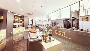A modern hotel kitchen with a buffet setup, marble flooring, and contemporary decor.