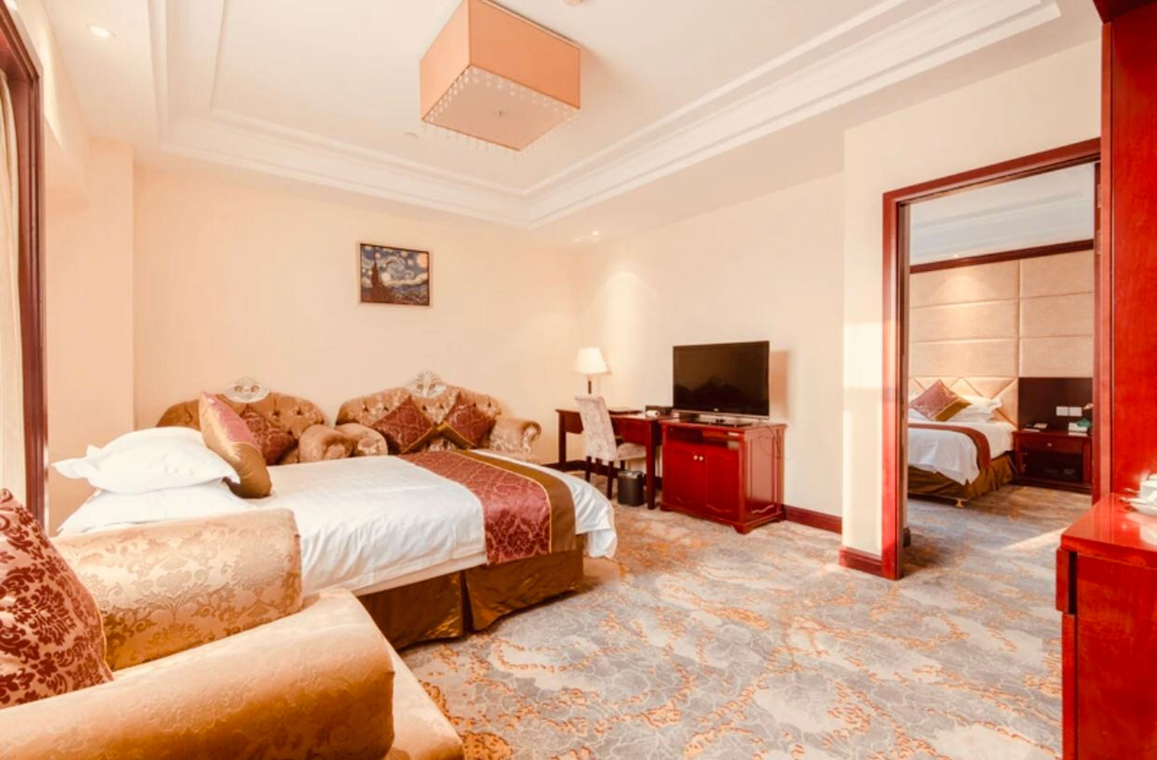 A hotel room with a large bed, a sofa, a TV, and a desk.