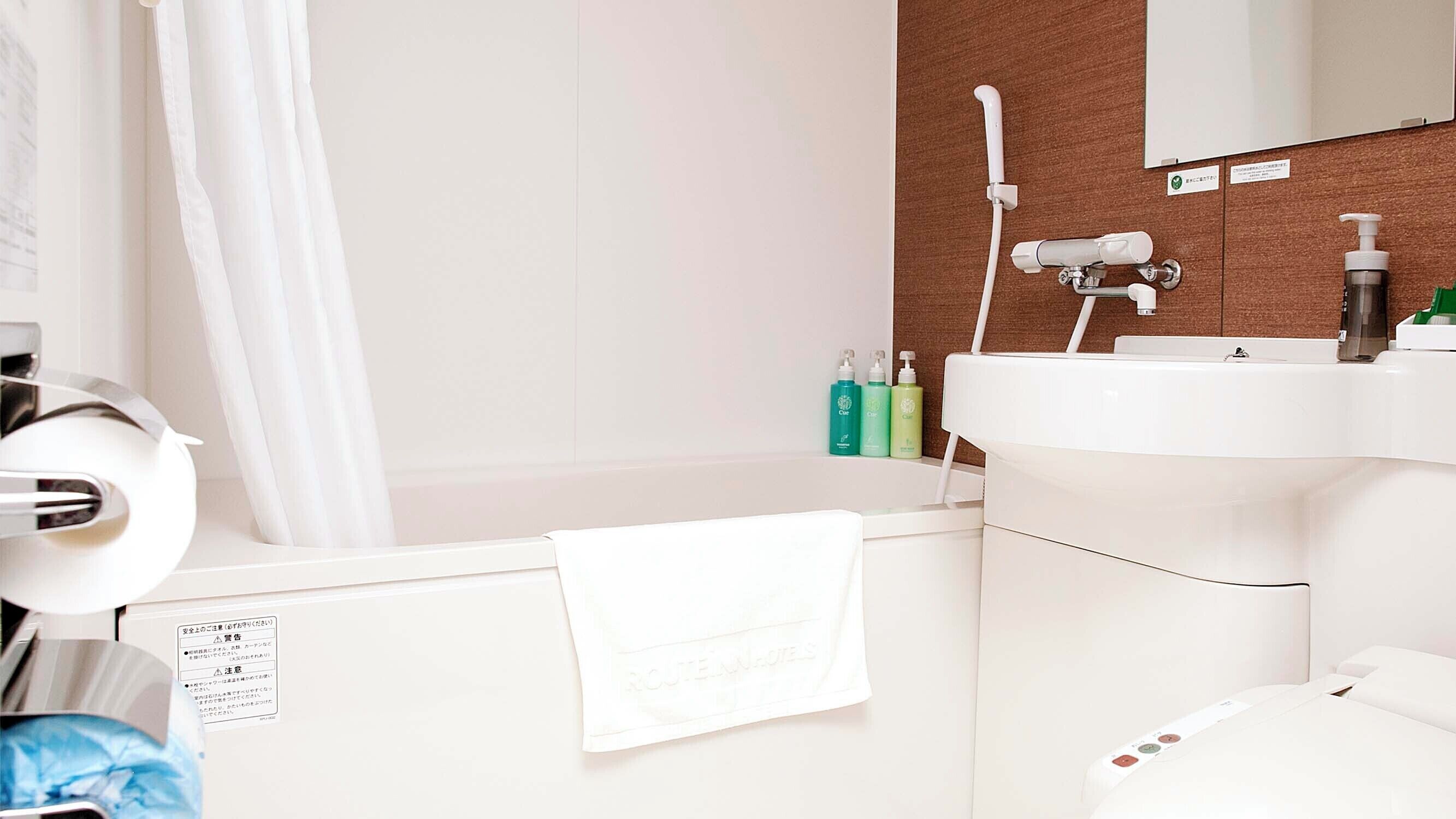A bathroom with a white sink, a towel hanging on the wall, and toiletries on the counter.