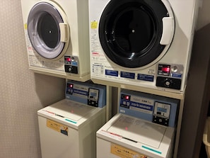 A laundry facility with two front-loading washing machines and two stacked dryers. - Hotel Route-Inn Gotenba Ekiminami (Gotemba)