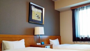 Ein Hotelzimmer mit zwei Betten, einem Nachttisch mit Lampe, einem gerahmten Bild an der Wand und einem Fenster mit Vorhängen.