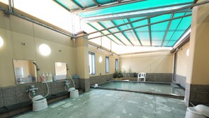 Ein Poolbereich mit gefliestem Boden, einer Duschgelegenheit mit Waschbecken und einem Stuhl.