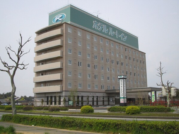 Un hotel de varios pisos con fachada verde y beige, múltiples ventanas y un cartel que indica que es un hotel.