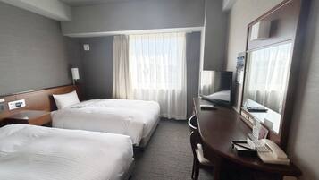 A hotel room with two beds, a desk with a telephone, a television, and a large mirror.