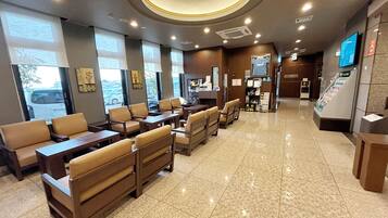 A hotel lobby with seating areas, a reception desk, and a vending machine.