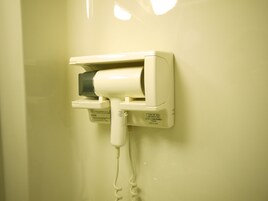 Un secador de pelo fijado a la pared con cable.