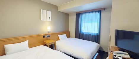 Een hotelkamer met twee bedden, een televisie, een bureau en een raam met gordijnen.