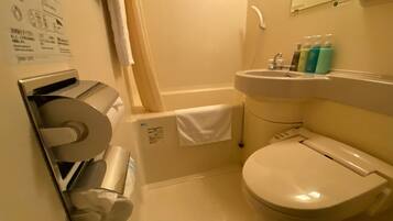Une petite salle de bain équipée de toilettes, d’un lavabo et d’un distributeur de serviettes en papier.