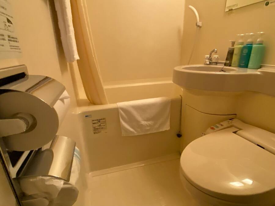 Une petite salle de bain équipée de toilettes, d’un lavabo et d’un distributeur de serviettes en papier.