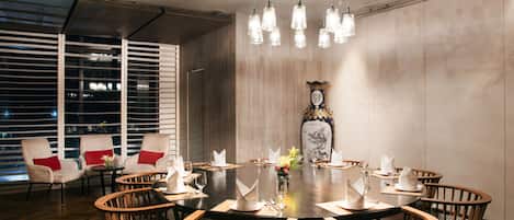 A dining area with a round table, wooden chairs, and a chandelier.