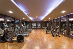 A gym with multiple treadmills, stationary bikes, and exercise balls.