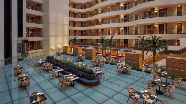 Atrio d'hotel a più livelli con posti a sedere all'aperto, balconi e una passerella centrale.