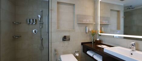 A modern bathroom with a glass-enclosed shower, a white toilet, a large mirror, and a dark vanity with a sink.
