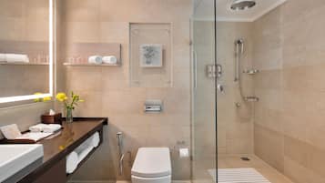 A modern bathroom with a glass-enclosed shower, a white toilet, a vanity with a mirror, and a towel rack.