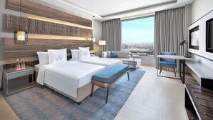 Camera d'albergo moderna con un letto grande, una scrivania, una televisione e vista sulla città.