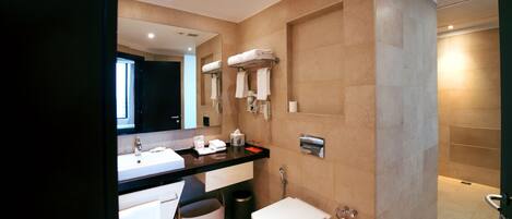 A modern bathroom with a large mirror, a white sink, a toilet, and a towel rack.