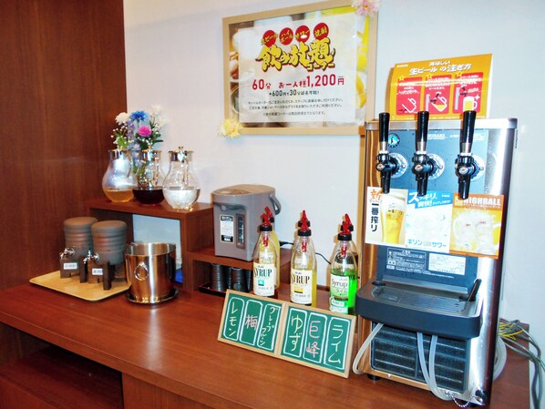 Uma área de bar com máquina de café, garrafas de xarope e um quadro de cardápio.