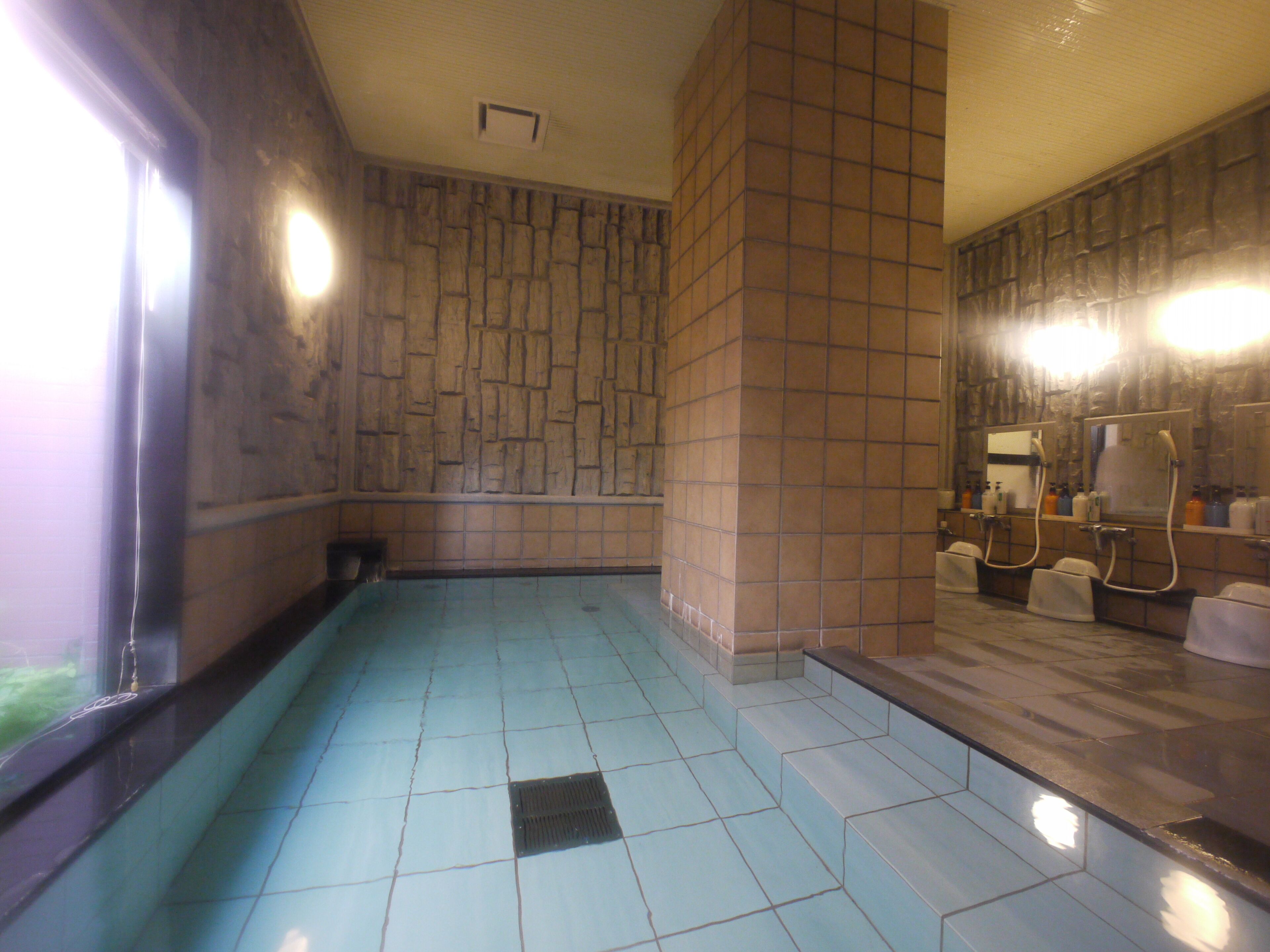 Ein Badezimmer mit Fliesenboden, Duschbereich und Waschbecken mit Spiegel.