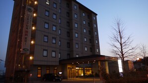 Un hotel de varios pisos con un diseño moderno, que cuenta con una entrada destacada con zona cubierta y un estacionamiento al frente.