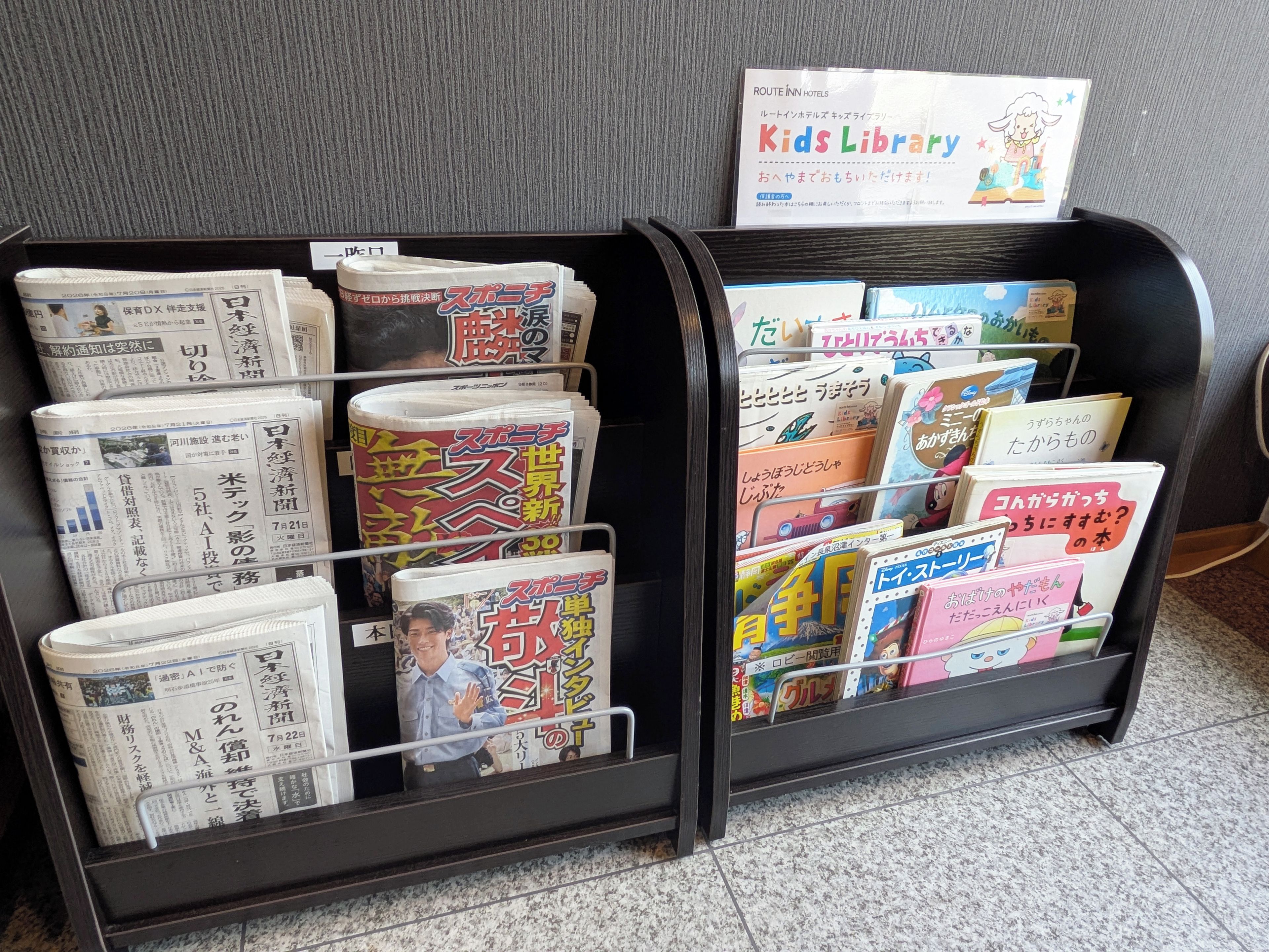 A magazine rack with various publications, including a sign for a Kids Library.