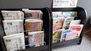 A magazine rack with various publications, including a sign for a Kids Library.