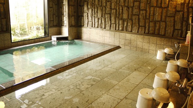 A stone-walled room with a large rectangular pool, a bench, and a row of toilets. - Hotel Route-Inn Nagaizumi Numazu Inter 1 (Nagaizumi)