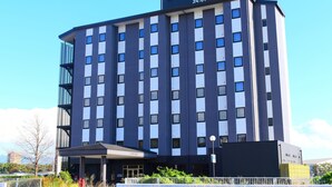 A multi-story hotel with a modern design, featuring a prominent sign at the top. - Hotel Route-Inn Nagaizumi Numazu Inter 1 (Nagaizumi)
