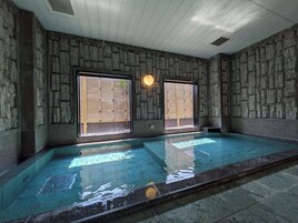 Una piscina con paredes de piedra y amplias ventanas.