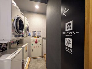 Une buanderie équipée d’un lave-linge, d’un sèche-linge et d’un panneau de commande muni d’un extincteur.