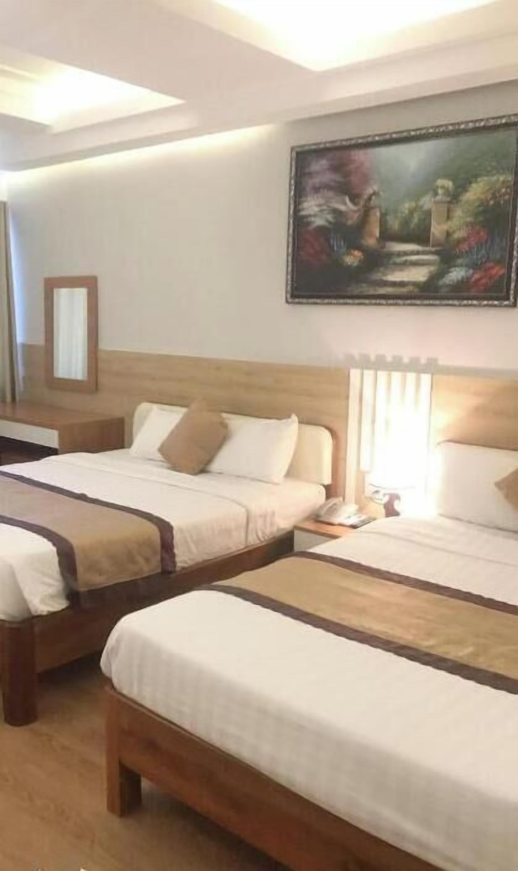 Habitació d'hotel amb dos llits, un quadre a la paret i una tauleta de nit amb una làmpada.