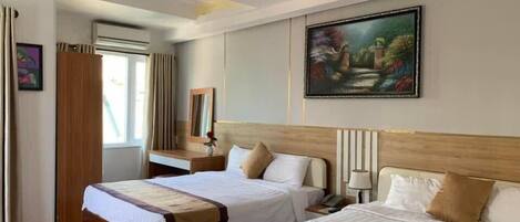 A hotel room with two beds, a wooden headboard, a painting on the wall, and a window with curtains.