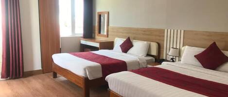 A hotel room with two beds, a wooden headboard, a desk, and a mirror.