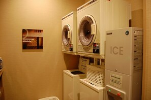 A laundry area with two front-loading washing machines and a dryer stacked on top of each other. - Hotel Route Inn Furukawa Ekimae (Osaki)