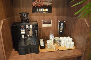 A self-service coffee station with a coffee machine, cups, and a sign indicating operating hours. - Hotel Route Inn Furukawa Ekimae (Osaki)