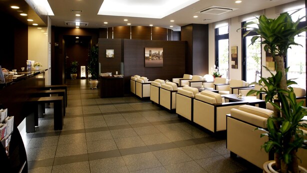 A hotel lobby with a reception desk, seating area, and a large window. - Hotel Route Inn Ishinomaki Kanan Inter (Isinomaki)
