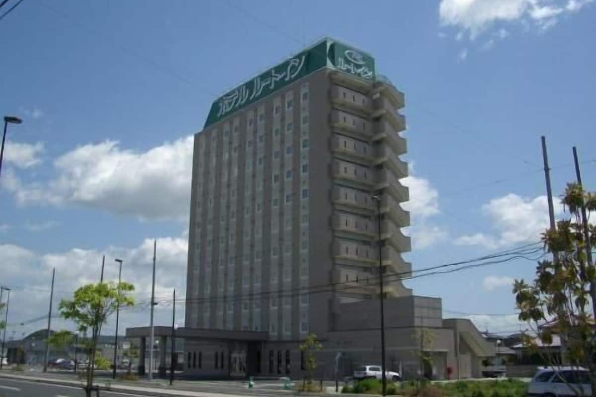Un hotel alto con un letrero verde en la parte superior, varios pisos y un techo plano.