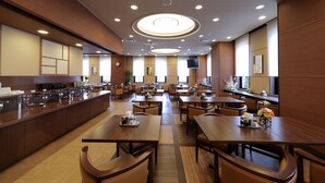 A spacious hotel dining area with multiple tables and a central bar.
