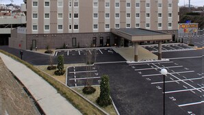 A multi-story hotel with a prominent sign, a parking lot, and a small covered area in front.