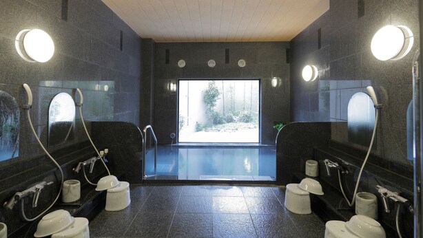 A modern bathroom with multiple toilets, sinks, and a large window providing natural light.