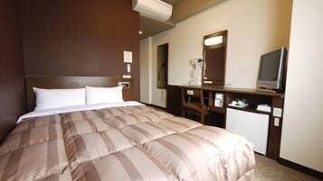 A hotel room with a large bed, a desk with a computer, a TV, and a mirror.